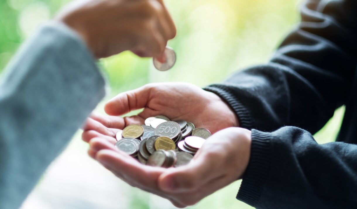 closeup image of a hand putting coins into another zf32uur